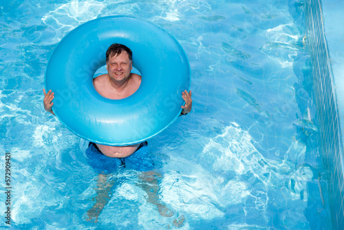 Male tourist with an inflatable ring in the pool close up.