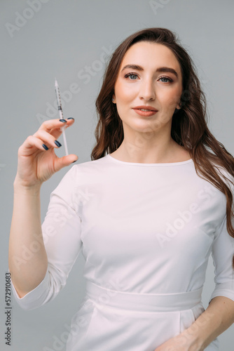 young woman doctor in a white coat holds an insulin syringe in her hand. Girl cosmetologist preparing to make an injection of botulinum toxin in a cosmetology clinic