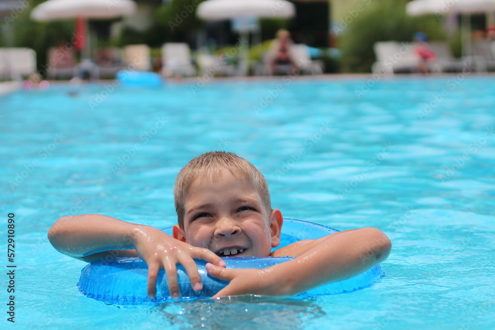 Happy little boy swims in the pool in summer, space for text