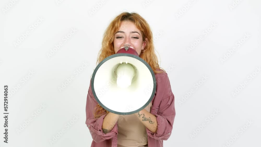 Young redhead woman shouting through a megaphone over isolated background Young redhead woman shouting through a megaphone over isolated background