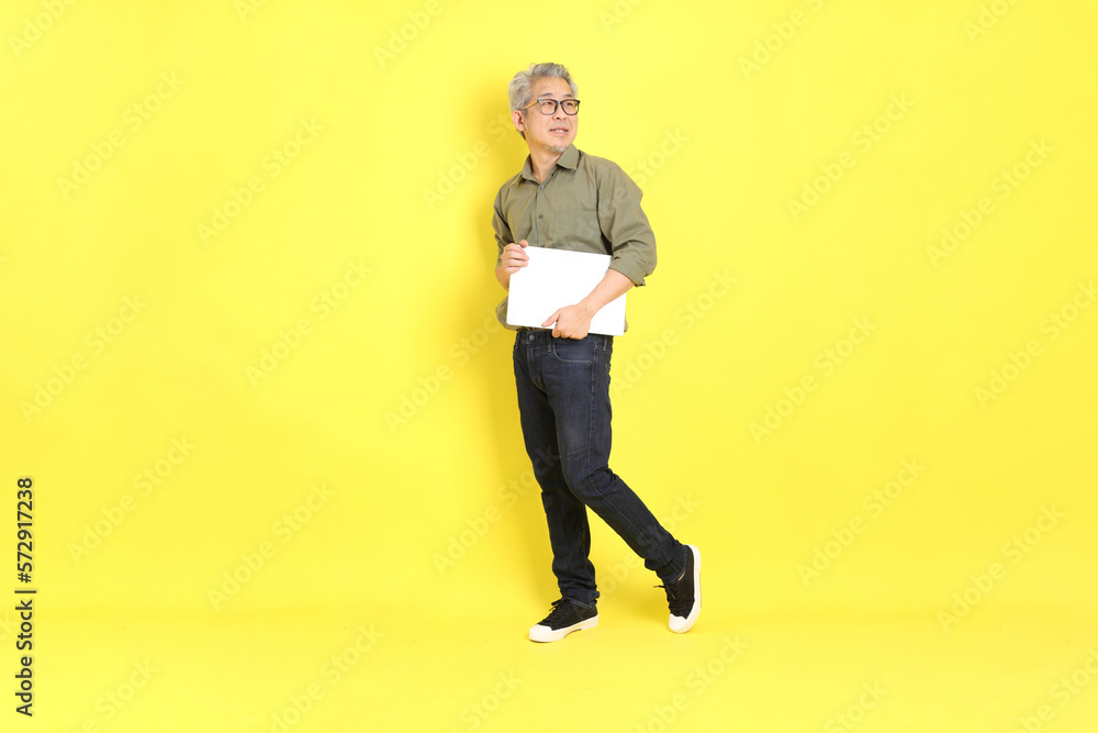 The 40s adult Asian man with casual dressed standing on the yellow background. The 40s adult Asian man with casual dressed standing on the yellow background.