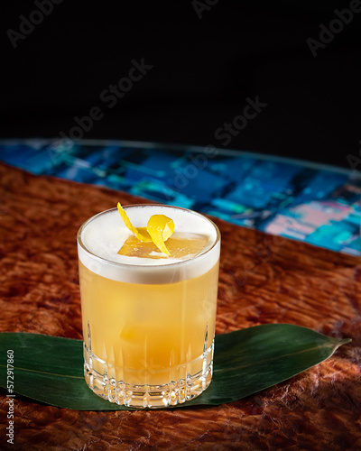 Obraz na płótnie Cocktail at the bar on brown leather background. Whisky amaretto sour with lemon zest garnishment. Modern, stylish alcoholic drink at restaurant. Beautiful beverage mix made with bourbon. Vertical w salonie