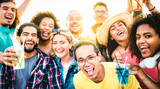 Multiracial friends taking selfie at sunset concert on vacation day - Party life style concept with young people having fun together at spring break beach festival - Vivid filter with sunshine halo