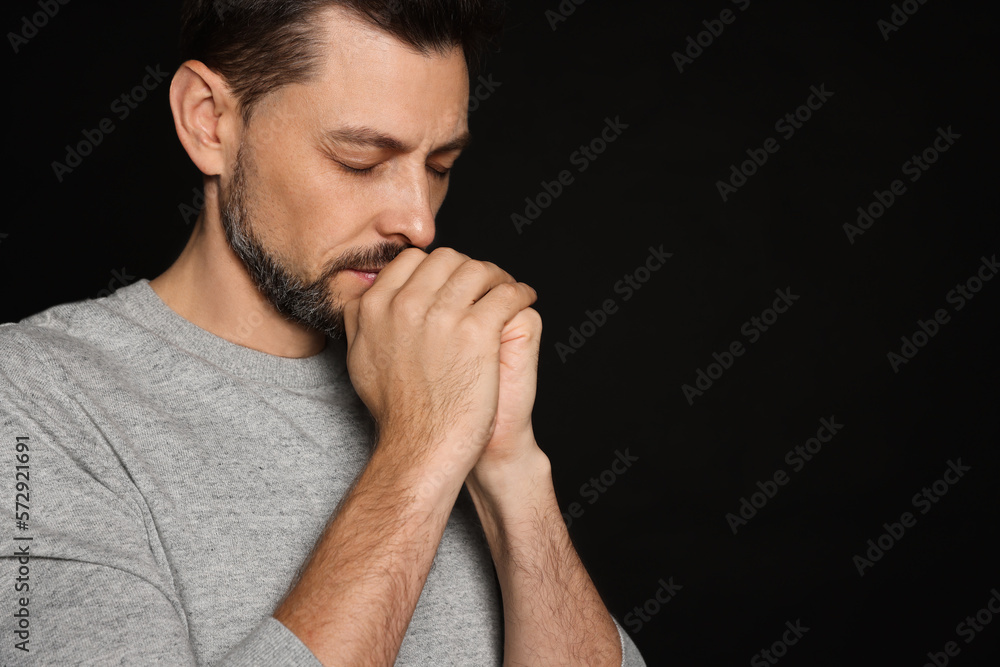 Man with clasped hands praying on black background. Space for text Man with clasped hands praying on black background. Space for text