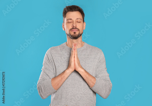 Fotografia Man with clasped hands praying on turquoise background