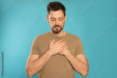 Fotografia Man with clasped hands praying on turquoise background
