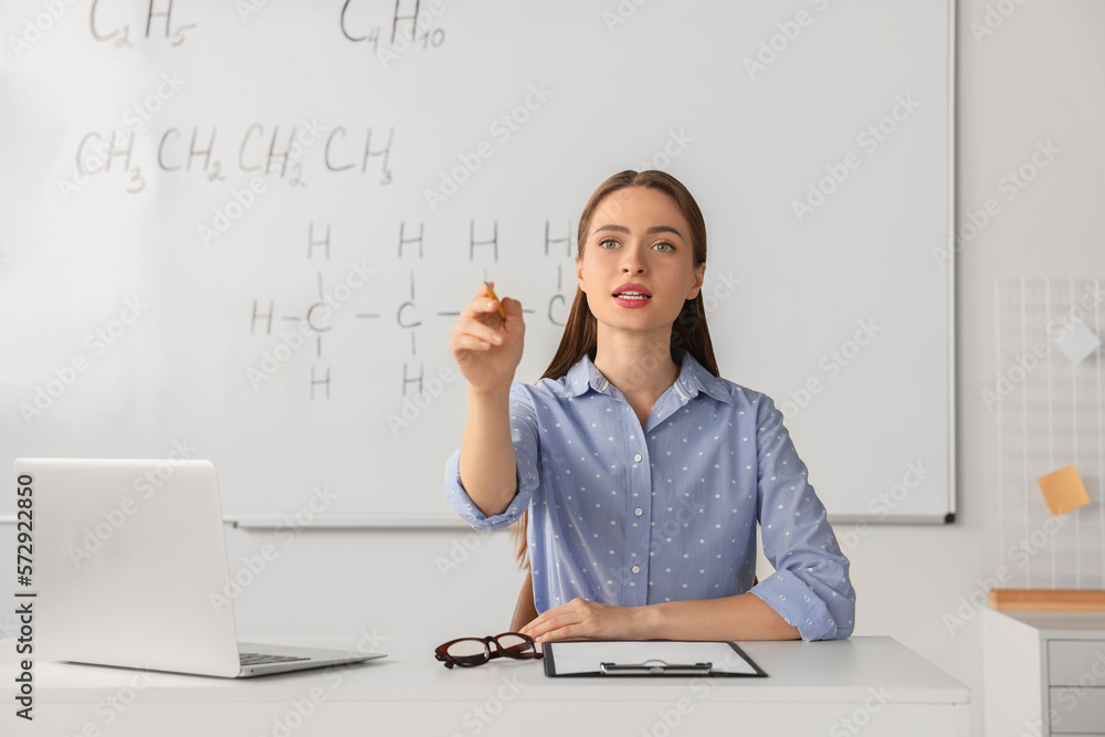 Young chemistry teacher giving lesson at table in classroom Young chemistry teacher giving lesson at table in classroom