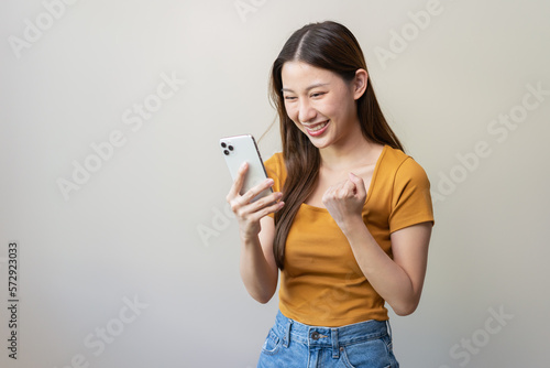 Happy Asian woman holding a smartphone and winning the prize.