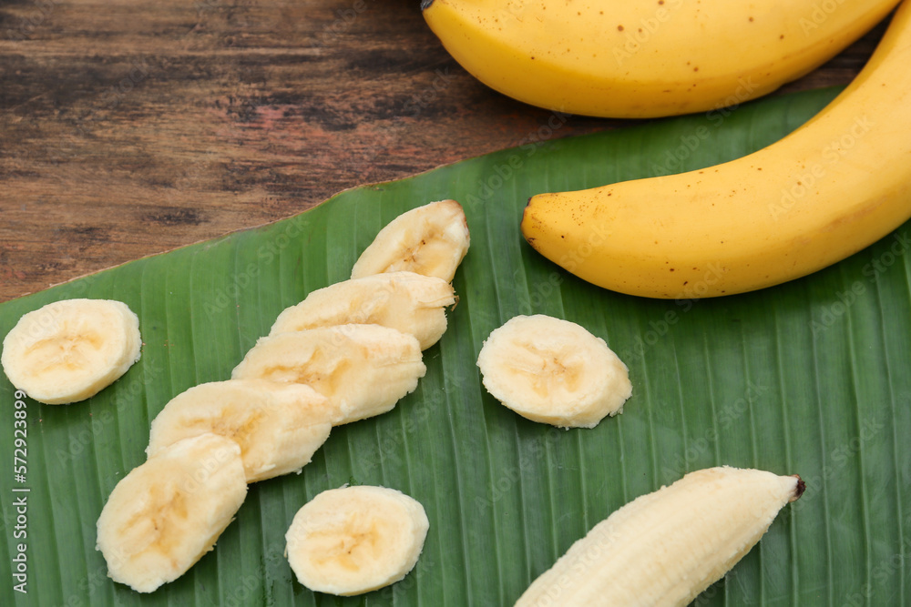 Delicious ripe bananas and fresh leaf on wooden table, above view