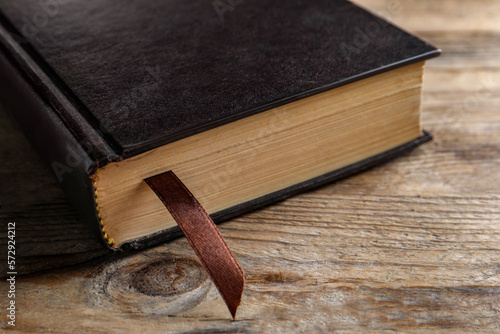 Fotografie Bible with dark cover on wooden table, closeup