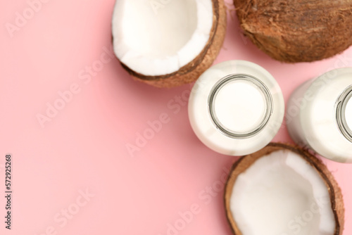 Delicious vegan milk and coconuts on pink background, flat lay. Space for text