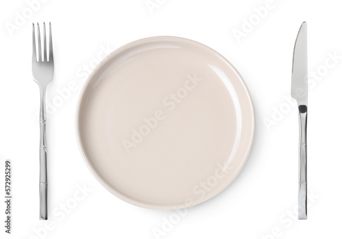 Empty beige plate with fork and knife on white background, top view
