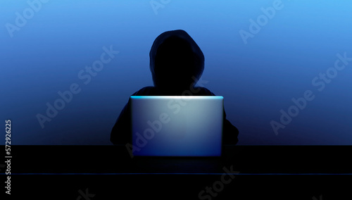 Dunkle Person mit Kapuze als Silhouette vor einem geöffneten Laptop und digit...