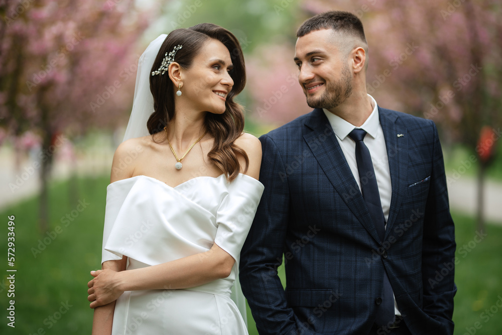 newlyweds walk in the park among cherry blossoms newlyweds walk in the park among cherry blossoms