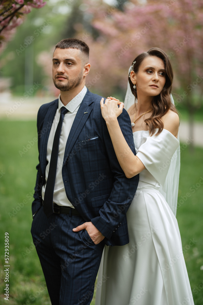 newlyweds walk in the park among cherry blossoms newlyweds walk in the park among cherry blossoms