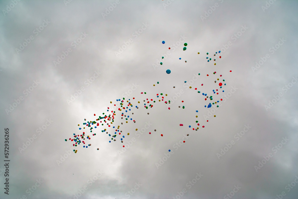 Fototapeta premium colored Baloons floating away against a stormy grey sky