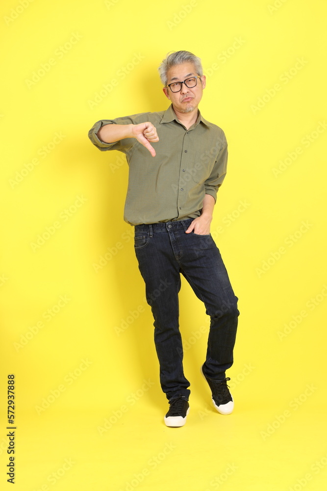The 40s adult Asian man with casual dressed standing on the yellow background.