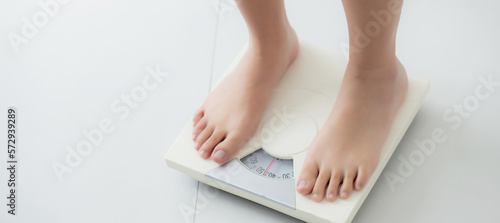 Closeup foot of woman standing on scales measuring for control weight in the room, overweight and dieting, health and weightloss, examining fat with weighing, indoor, healthy concepts. photo