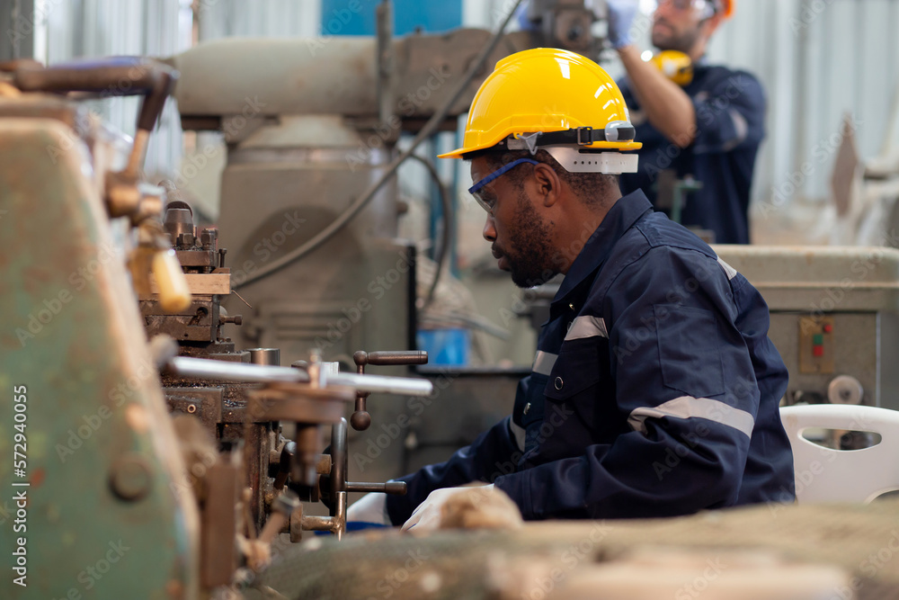 Young black engineer man operating lathe machine for preparing production at factory industrial, technician or labor maintenance machinery at workplace, metalworker working, industry concept. Young black engineer man operating lathe machine for preparing production at factory industrial, technician or labor maintenance machinery at workplace, metalworker working, industry concept.