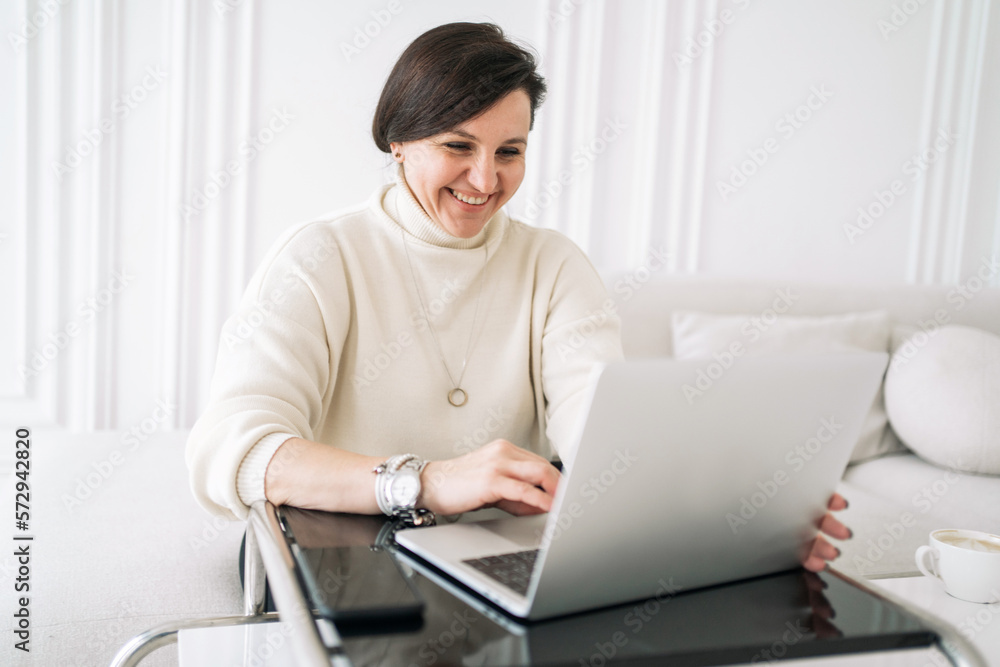 A freelance psychologist woman is stylish, cheerful, working using a laptop, a new stylish home office. A freelance psychologist woman is stylish, cheerful, working using a laptop, a new stylish home office.