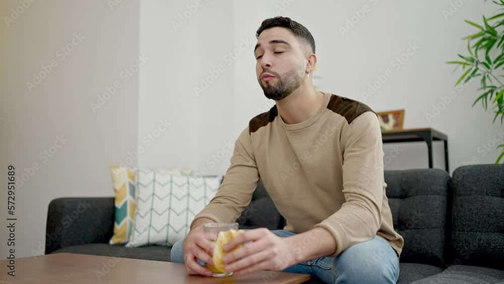 Young arab man having breakfast sitting on sofa at home Young arab man having breakfast sitting on sofa at home