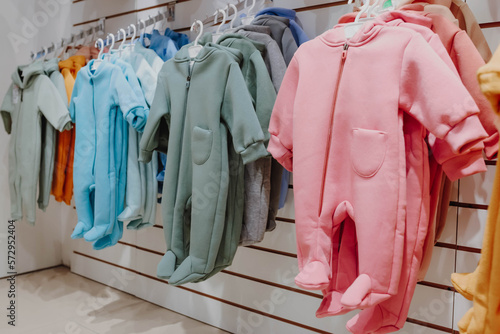 Bright spring jumpsuits for newborns hang on hangers in a children's clothing store