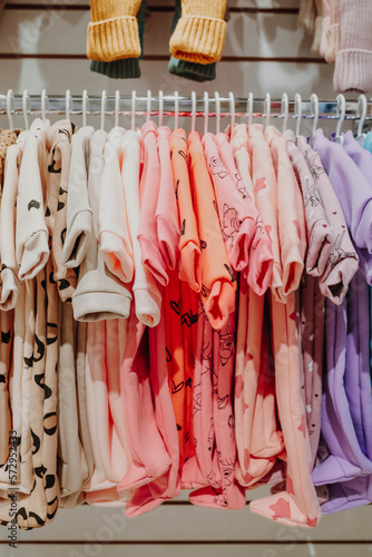 Bright spring jumpsuits for newborns hang on hangers in a children's clothing store