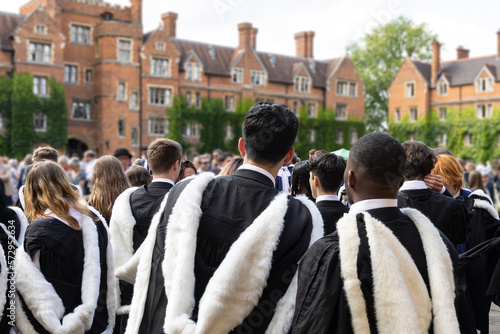 back view of Male and female fresh British Black African graduate students with gown and academic address walk in campus of  University, UK during congregation day.