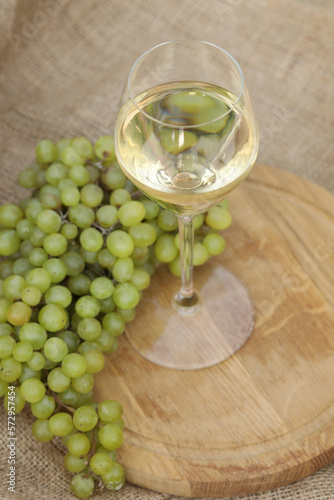 glass of white wine on wooden background with  grape