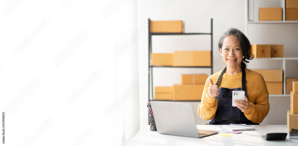Asian senior small business owner using her smartphone to contact with her customer to get more detail. Asian senior small business owner using her smartphone to contact with her customer to get more detail.