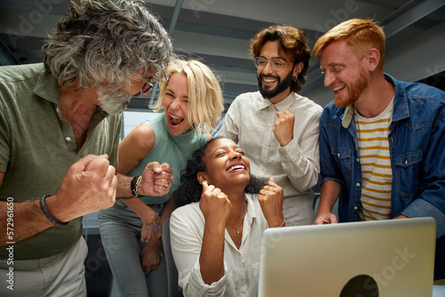 In the modern office a group of colleagues of different ages and ranks celebrate a business success. Workers from the same team rejoice at the company's progress. Happy entrepreneurial people.