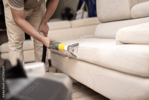 Cleaning a dirty sofa with a sofa washer. Close up of hands holding sofa cleaner. Professional sofa wash. Sofa wash image