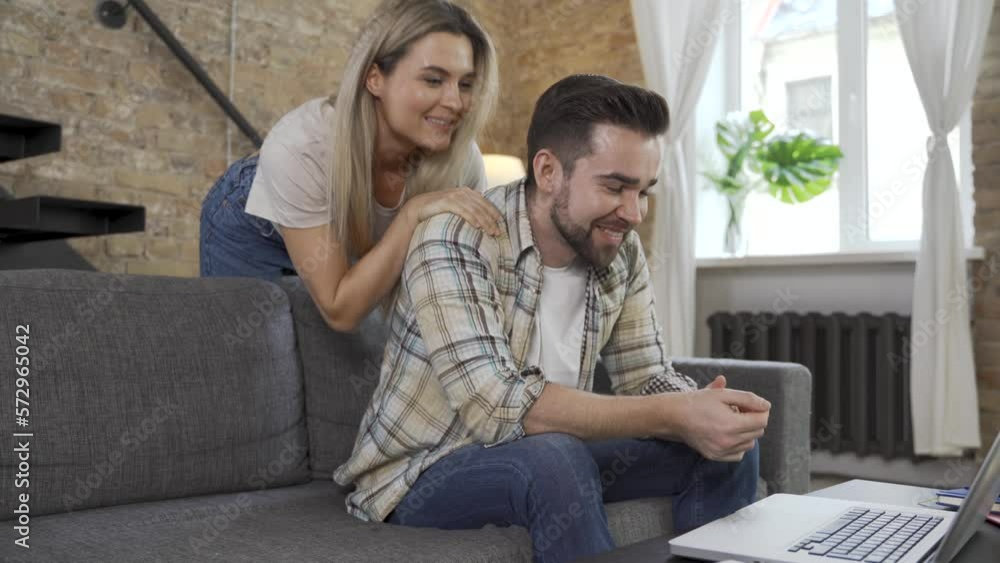 Happy couple using laptop for video call in the living room Happy couple using laptop for video call in the living room