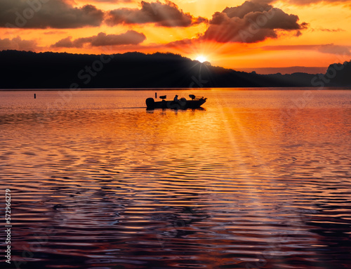 Silhouette of bass fishermen in a fishing boat on the lake, early morning sunrise on Tims Ford Lake in Tennessee, USA.