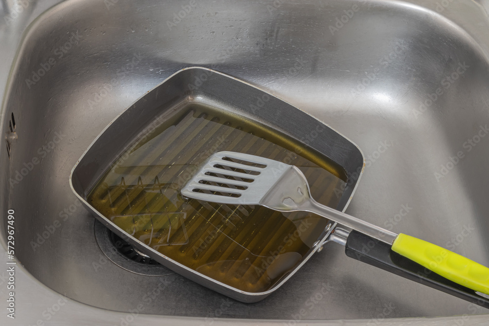 Wash the pan and pour the old oil into the sink. causing clogged sinks and drains. Stock Photo