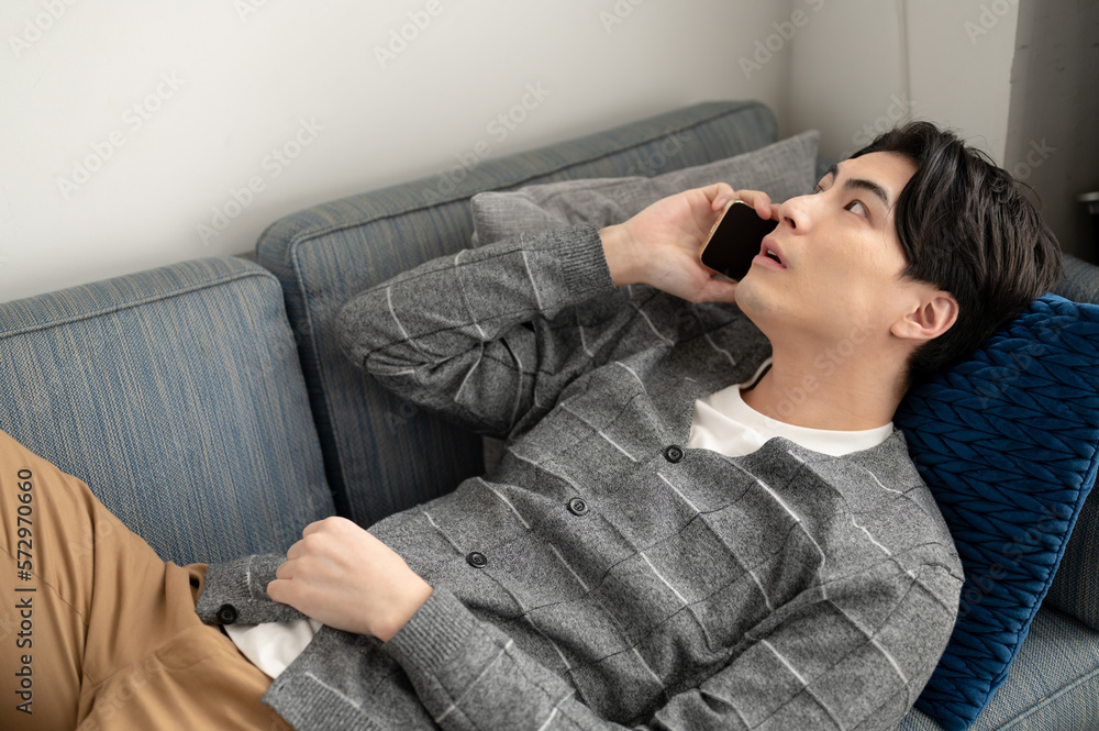 ソファで寛ぎ電話する男性 ソファで寛ぎ電話する男性