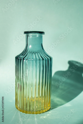 Φωτογραφία A glass bottle is a flower vase. Shadow. Turquoise background
