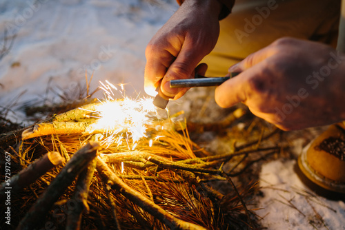 Closeup of male hand starts fire with magnesium fire steel, fire striker. Survival concept
