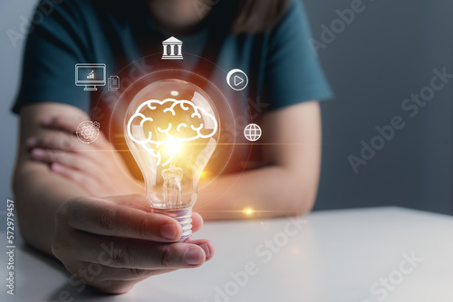 AI (Artificial Intelligence), financial ecosystem, businessman hold light bulb showing banking, graph and entertainment icons, digital transformation, fintech, technology.