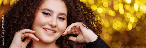 Tableau sur toile Banner beautiful,confident woman plus size model with long curly hair in black clothes stands on a shiny golden background