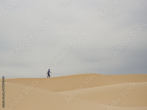 silhouette of middle-aged man walking alone in the desert through sand barkhans in South American desert