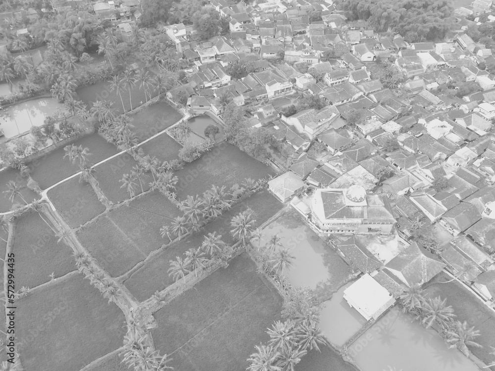 Black and white photo of an aerial view of a rice field in the middle of a village settlement in the Cikancung area - Indonesia.