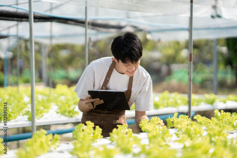 Young handsome Asian farm worker working in the farm while collect and write data on the document. Young handsome Asian farm worker working in the farm while collect and write data on the document.