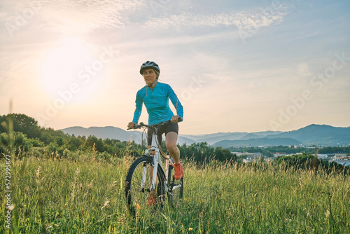 Cyclist Woman riding bike in helmets go in sports outdoors on sunny day a mountain in the forest. Silhouette female at sunset. Fresh air. Health care, authenticity, sense of balance and calmness. 