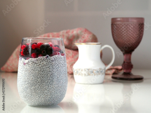 Chia Seed Pudding with Red Berries in the big glass on a light table.