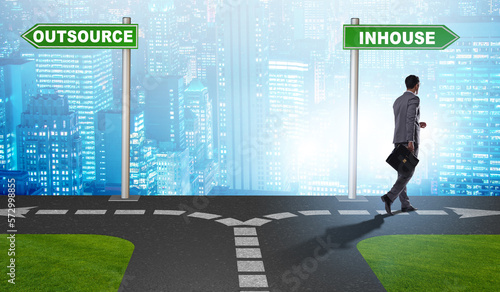 Businessman at crossroads deciding between outsourcing and inhou