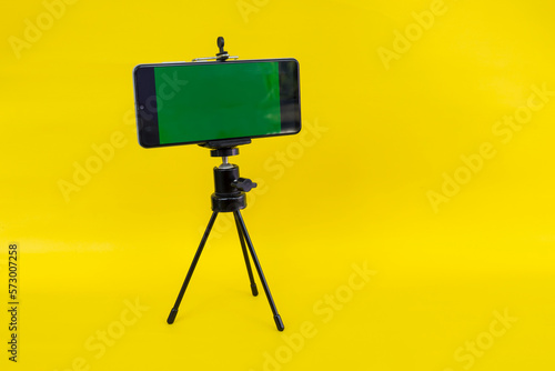 Black mini tripod with steel case, ballhead and smartphone with greenscreen photo