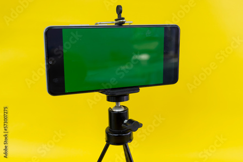 Black mini tripod with steel case, ballhead and smartphone with greenscreen photo