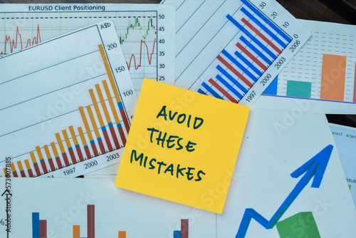Concept of Avoid These Mistakes write on sticky notes isolated on Wooden Table. Stock market concept