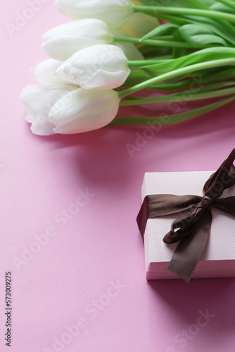 White tulips on a pink background and a gift. holiday.